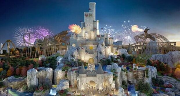 A grand castle with multiple towers stands illuminated against a twilight sky in what feels like a UK-themed Disneyland. Surrounding the castle are amusement park rides, colorful trees, and bursts of fireworks. Flamethrowers create spectacular flames, adding a magical feel to the theme park scene.