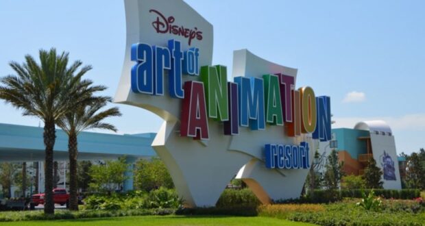 The image shows the colorful entrance sign for Disney's Art of Animation Resort at Walt Disney World. The words "Art of Animation" are prominently displayed in large, multicolored letters, surrounded by lush greenery and palm trees in the background.