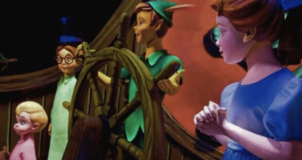A group of animated characters is shown on a ship. A boy wearing green clothes and a hat with a feather stands at the ship's wheel. To his left is a girl in a blue dress. Both are standing with two other children, one in pink pajamas and another with glasses, reminiscent of a magical day at Disney World.