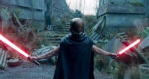 A figure stands in a desolate, overgrown area, holding two red lightsabers with arms outstretched. The person is wearing a helmet and cape, adding to an ominous presence amidst the rundown, post-apocalyptic surroundings.