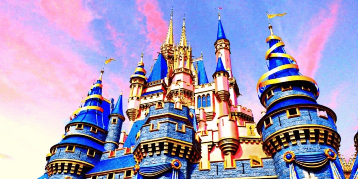 A vibrant castle with blue and gold turrets set against a pink and blue sky. The structure features intricate detailing and a fairytale-like appearance, creating a magical atmosphere.