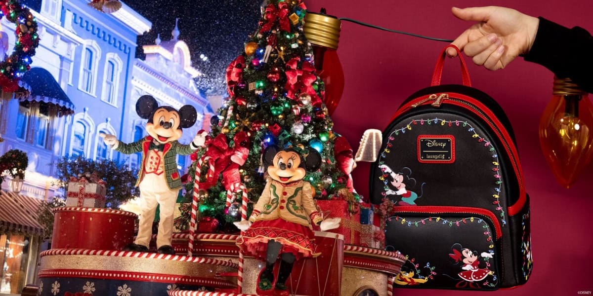 A festive scene with Mickey and Minnie Mouse in holiday outfits standing in front of a decorated Christmas tree. A hand holds a black Disney backpack with Mickey and Minnie designs, surrounded by hanging string lights.