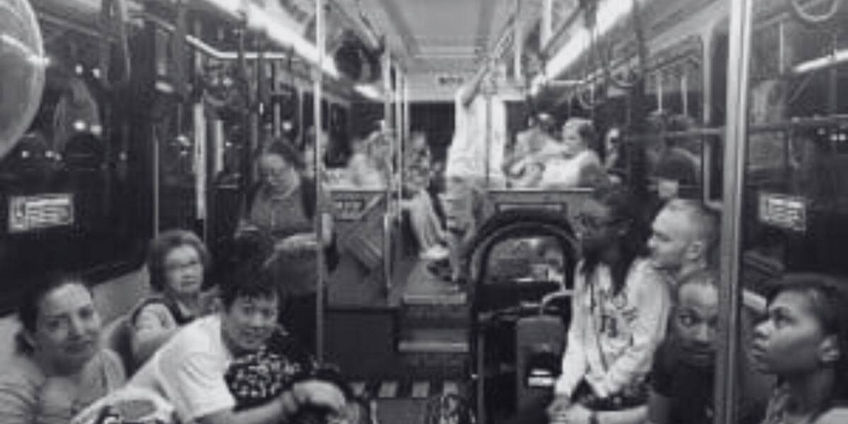 A black and white photo of people sitting inside a Disney bus.