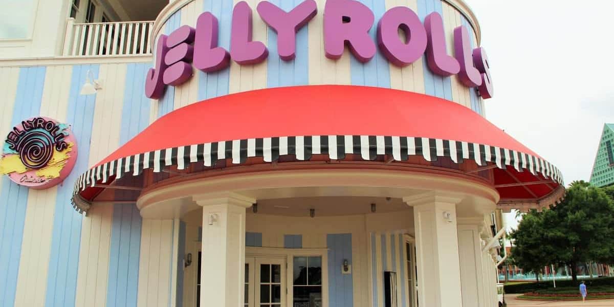 A colorful building features a sign with large purple letters spelling "Jellyrolls" above a red and white striped awning. The facade is blue and white striped, and there's a multicolored logo on the side wall.