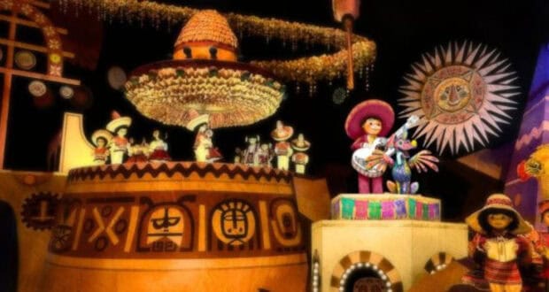 A vibrant scene with animatronic figures in colorful traditional Mexican attire playing instruments. The background features cultural symbols and decorations, including a large sombrero and sun motif, all illuminated with bright, festive lighting—perfectly capturing the spirit of Disneyland 70th celebrations.