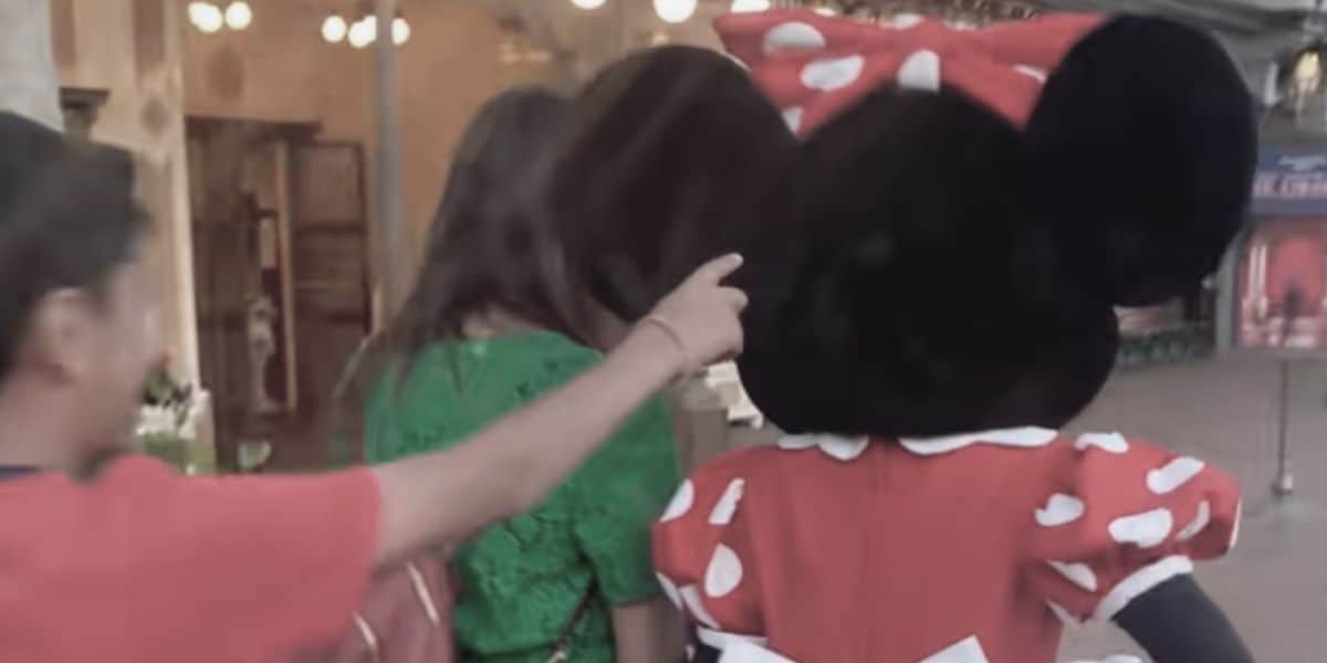 A child hitting Minnie Mouse on the ear from behind.
