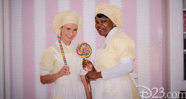 Main Street Confectionery cast members stand in front of the candy stripe wall at Magic Kingdom