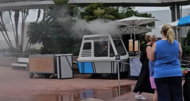 A small white and blue booth at EPCOT is on fire and smoking.