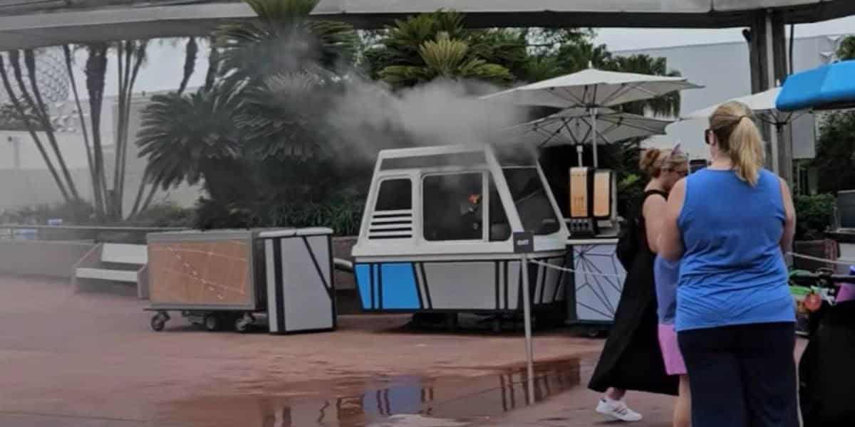 A small white and blue booth at EPCOT is on fire and smoking.