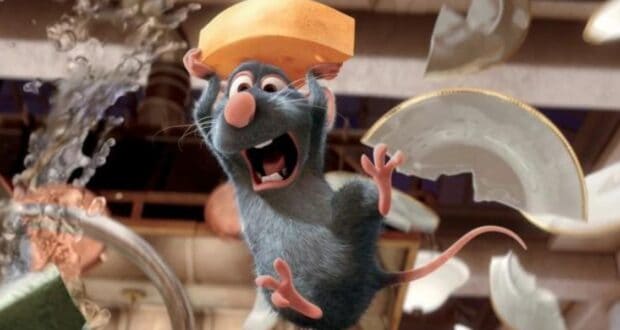 A cartoon rat with blue-gray fur holds a slice of cheese above its head and looks surprised, as broken plates and water fly around in a chaotic kitchen scene.