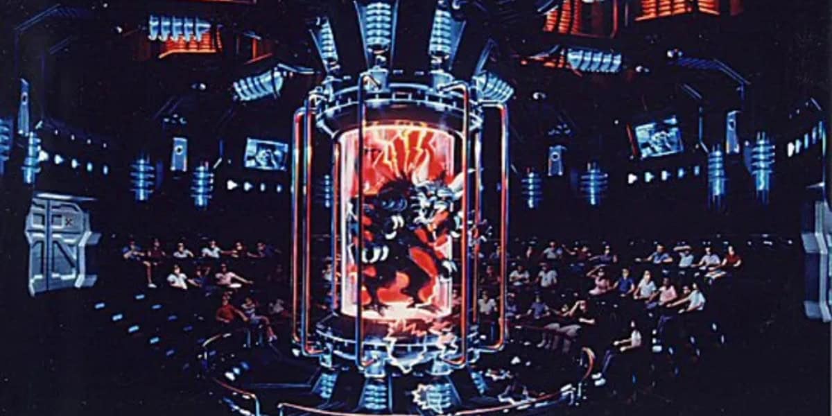A futuristic auditorium with people seated in rows, watching a large glass chamber in the center that contains a menacing alien creature surrounded by glowing red and blue lights. Monitors and high-tech equipment fill the dark room.