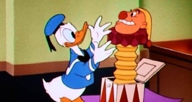 Donald Duck, dressed in his usual blue sailor outfit, looks surprised as he opens a jack-in-the-box with a clown popping out. The scene appears to be indoors with a green and brown background.