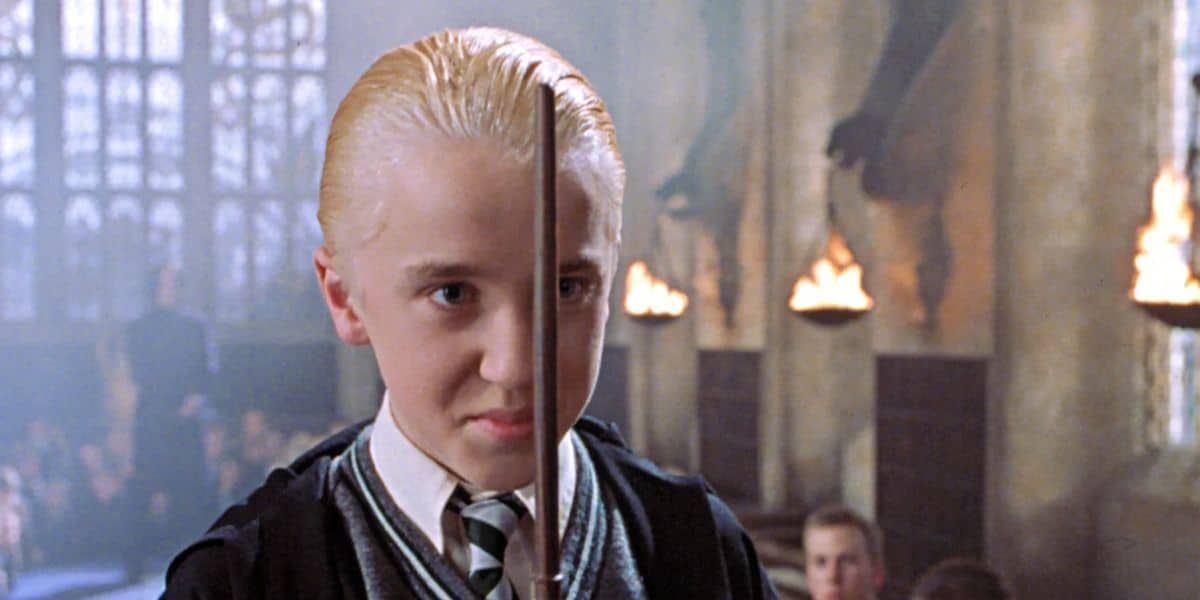 Tom Felton as Draco Malfoy holding his wand in front of his face