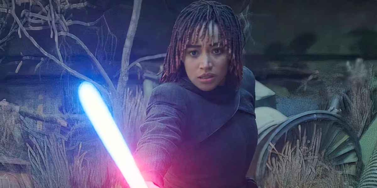 A determined woman with short, braided hair points a glowing blue lightsaber forward, standing amidst overgrown foliage and broken machinery in a dark, outdoor setting.