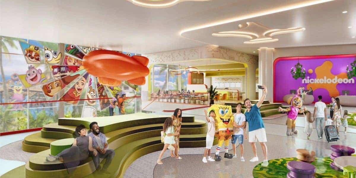 A lively indoor Nickelodeon-themed attraction with families posing for photos, a SpongeBob mascot, colorful decor, cartoon murals, and a giant orange blimp. The space feels bright and playful.