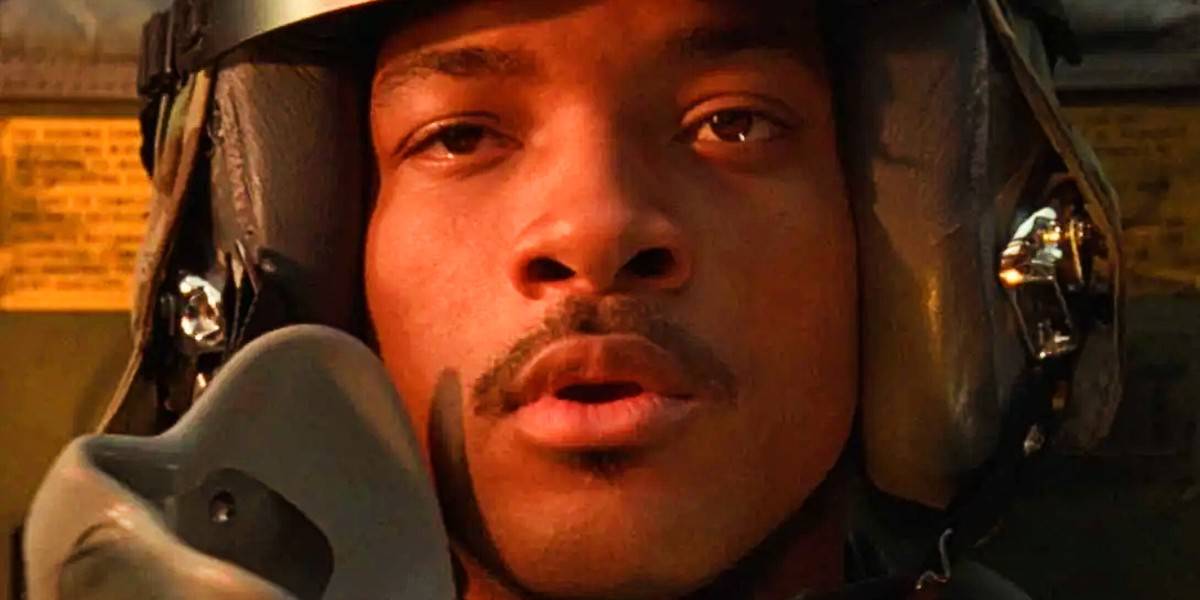 A close-up of a person wearing a helmet and flight gear, sitting in what appears to be a cockpit, looking forward with a focused expression.