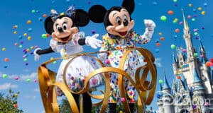 Mickey and Minnie Mouse, celebrating at Walt Disney World in colorful outfits, stand on a float with gold swirls amid flying confetti, with a castle in the background under a bright blue sky.
