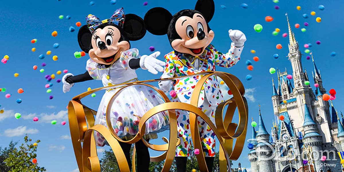 Mickey and Minnie Mouse, celebrating at Walt Disney World in colorful outfits, stand on a float with gold swirls amid flying confetti, with a castle in the background under a bright blue sky.