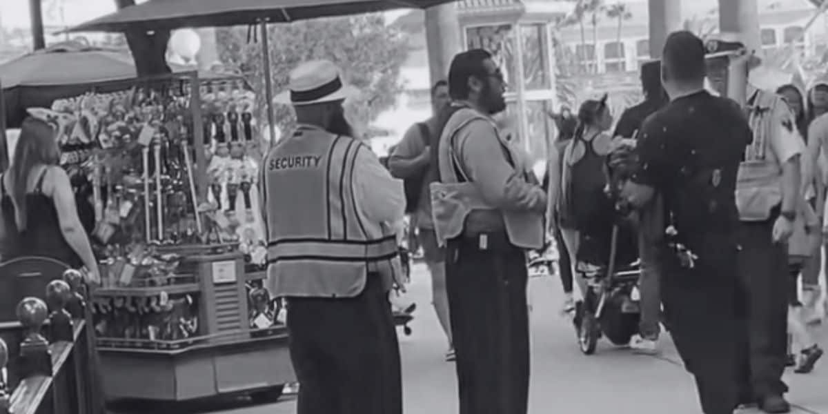 Disneyland Resort security talks to a drunk guest at Disney California Adventure Park. Image is in black and white.