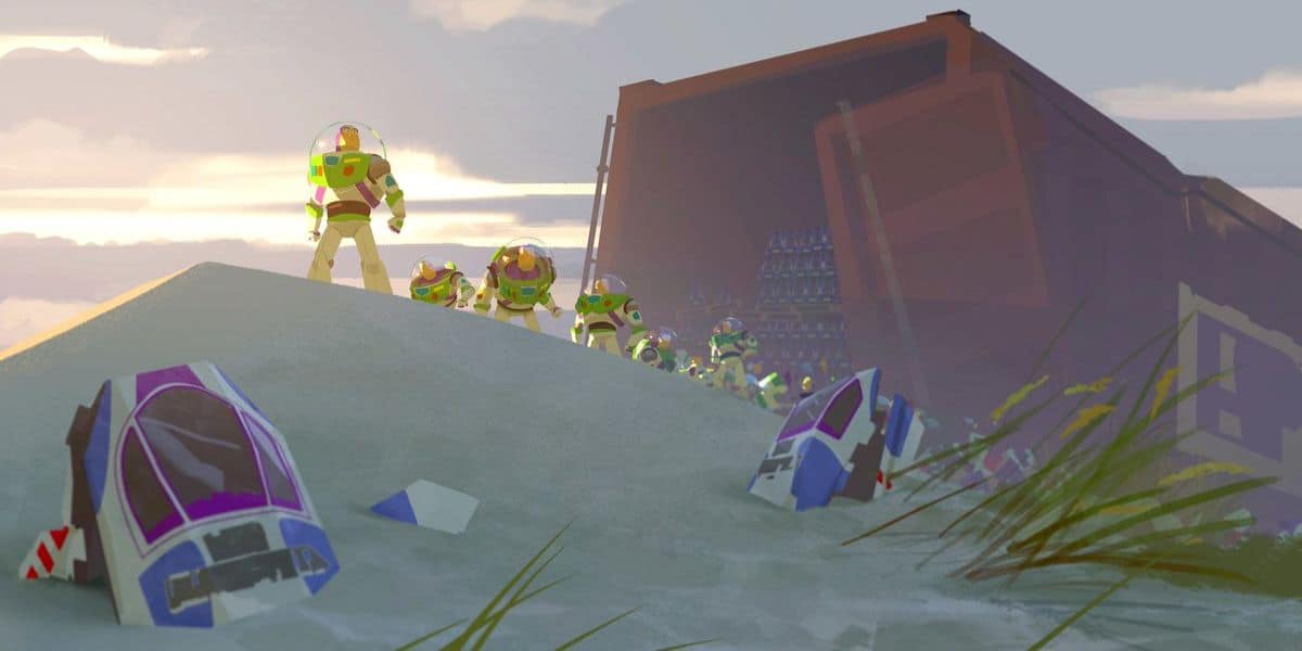 Several Buzz Lightyear action figures stand on a sandy hill near a crashed spaceship, with an open, dark container filled with more figures in the background. Grasses and debris scatter across the sand.