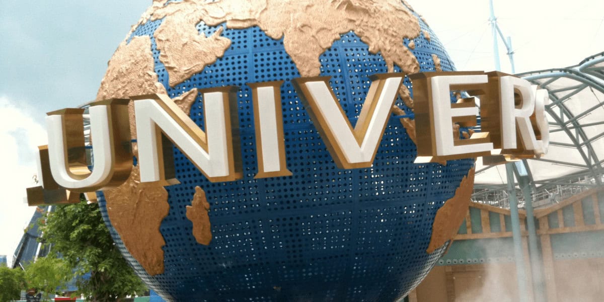 A large blue and gold globe with the word "UNIVERSAL" in bold white letters, located at the entrance of Universal Studios theme park.