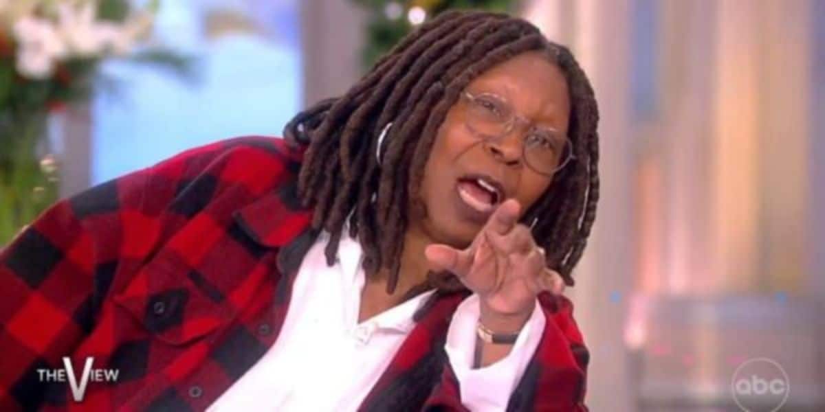 A woman with long dreadlocks and glasses, wearing a red and black plaid jacket over a white shirt, gestures animatedly while speaking on the set of "The View." The show's logo appears in the corner.