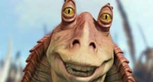 A close-up of Jar Jar Binks, a fictional alien character with yellow eyes and a wide smile, from the Star Wars movie series, against a blurred outdoor background.