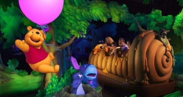 Winnie the Pooh floats with a pink balloon near guests on the beehive-themed ride at the park, now as a public domain icon.