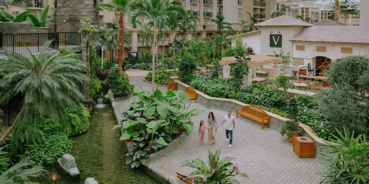 A family of three enjoys a scenic stroll through the lush indoor gardens at Epcot, surrounded by tropical greenery.
