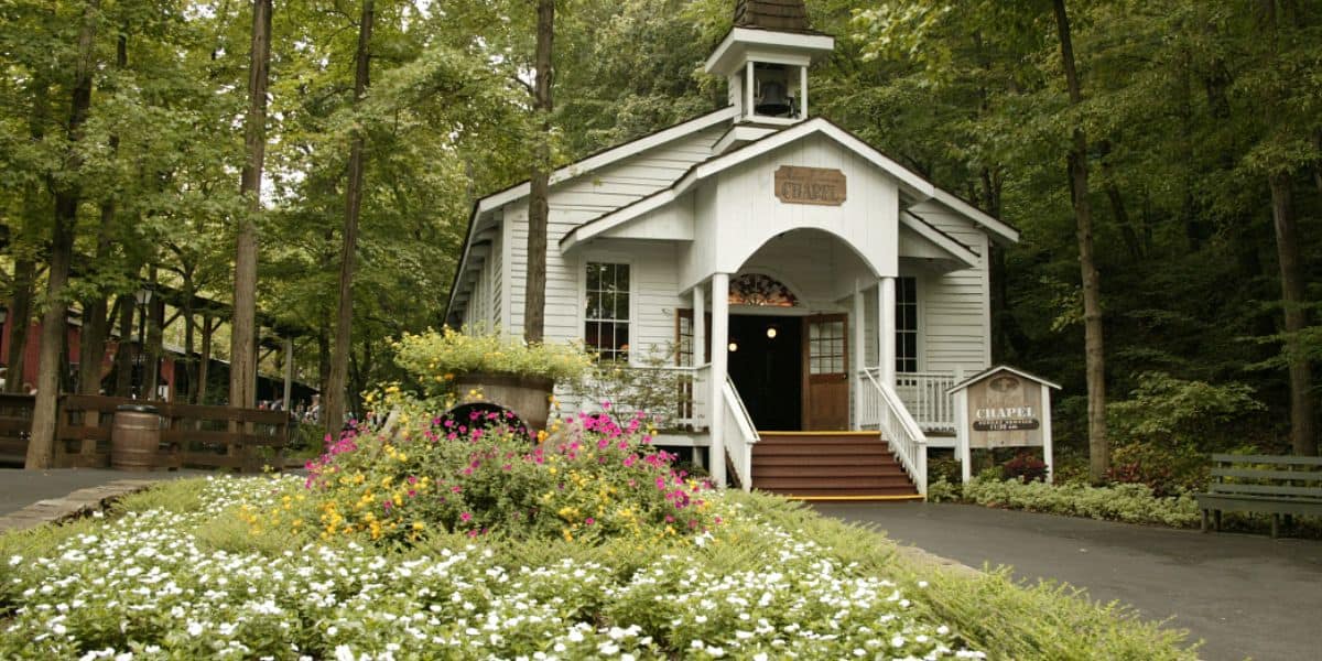 Dollywood’s white chapel with steeple sits among trees and bright flowers, offering guests a peaceful spot for weekly worship.