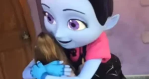 A beloved blue Disney character warmly embraces a young guest near a park entrance, capturing the magic of a character meet-and-greet.