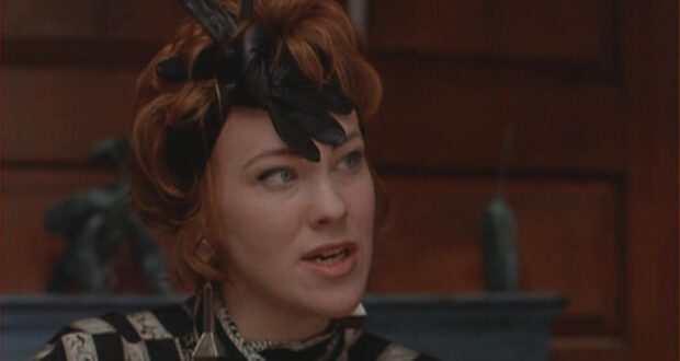 Catherine O'Hara, with signature red hair and a black feathered hat, delivers an emotional scene inside the Haunted Mansion.