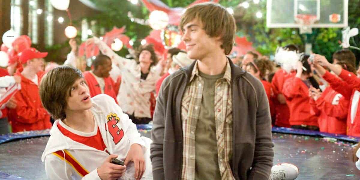 Two teens party outside amid crowds in Disney-inspired red and white, echoing the buzz after a Disney Channel star scandal.