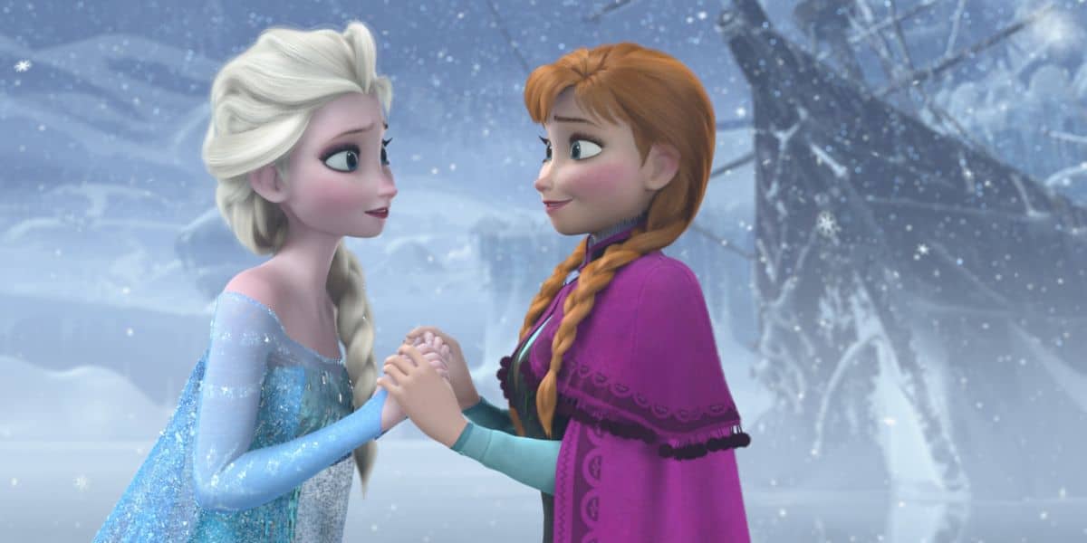Anna and Elsa clasp hands in the snow