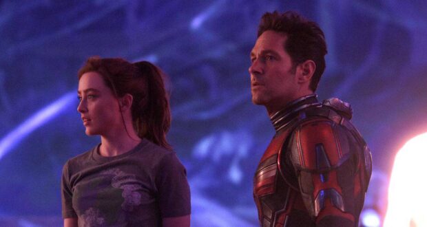 An Avengers: Doomsday hero poses beside a casually dressed guest under vibrant lights, capturing a thrilling park moment.