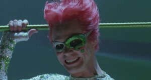 The Riddler dazzles with neon-pink hair, sparkling green mask and suit, brandishing a cane and flashing a showman’s grin.