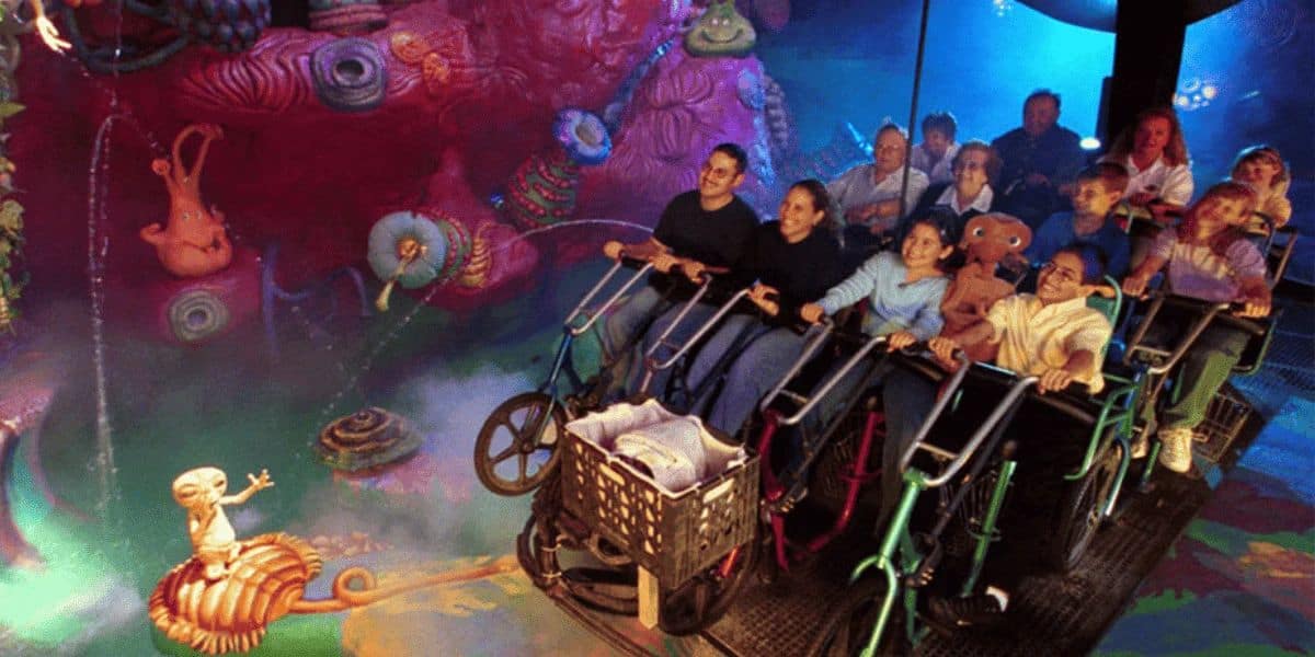 People riding a dynamic simulation ride with underwater-themed decorations including colorful coral and a character on bicycles inside of E.T. Adventure at Universal Studios Florida.