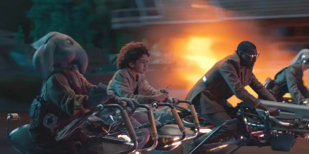Guests in vibrant costumes, including a rabbit-helmet rider, speed on hoverbikes past fireworks like a Mandalorian live show.