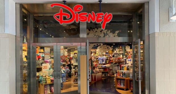 Disney Pop Up Store entrance with iconic red Disney logo, glass doors displaying merch; fans buzzing about its possible comeback.