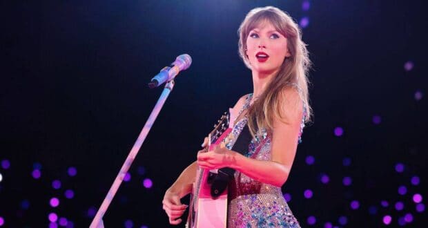 Taylor Swift dazzles in a glittering dress, rocking her guitar on stage amid purple lights as she teases Toy Story 5’s new song.