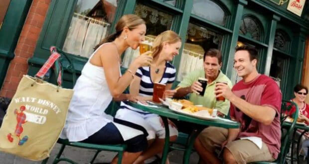 Four friends enjoying beers and food at an outdoor table at the Rose & Crown Pub in the Epcot United Kingdom pavilion.