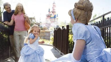 A young girl dressed as Cinderella meets Cinderella in front of Sleeping Beauty Castle at Disneyland Park.