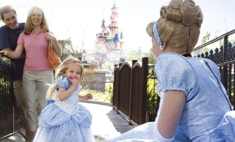 A young girl dressed as Cinderella meets Cinderella in front of Sleeping Beauty Castle at Disneyland Park.