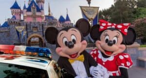 Mickey and Minnie Mouse pose in front of Sleeping Beauty Castle at Disneyland as a police car arrives for an investigation.