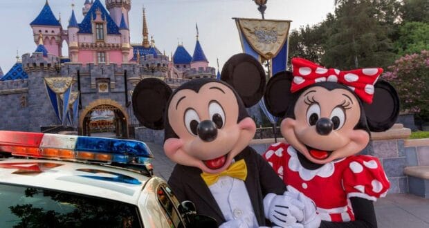 Mickey and Minnie Mouse pose in front of Sleeping Beauty Castle at Disneyland as a police car arrives for an investigation.