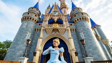 Cinderella poses in front of the iconic Cinderella Castle at Magic Kingdom in Walt Disney World.