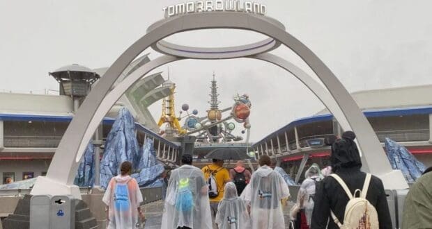 Guests pass beneath the Tomorrowland entrance arch at Magic Kingdom.