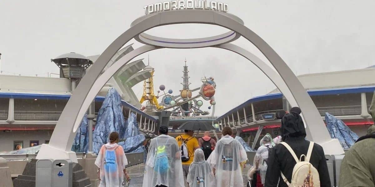 Guests pass beneath the Tomorrowland entrance arch at Magic Kingdom.