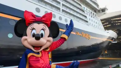 Minnie Mouse posing in front of the Disney Destiny cruise ship for vacation news.