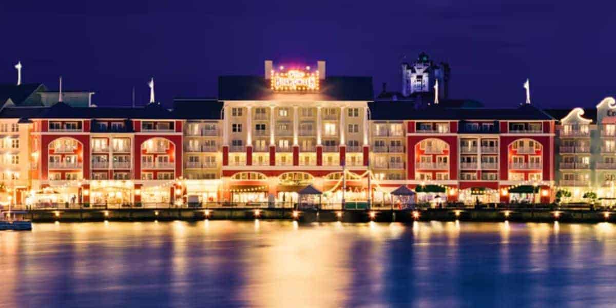 Disney’s BoardWalk Inn glowing at night, reflected in the water, in the latest resort update.
